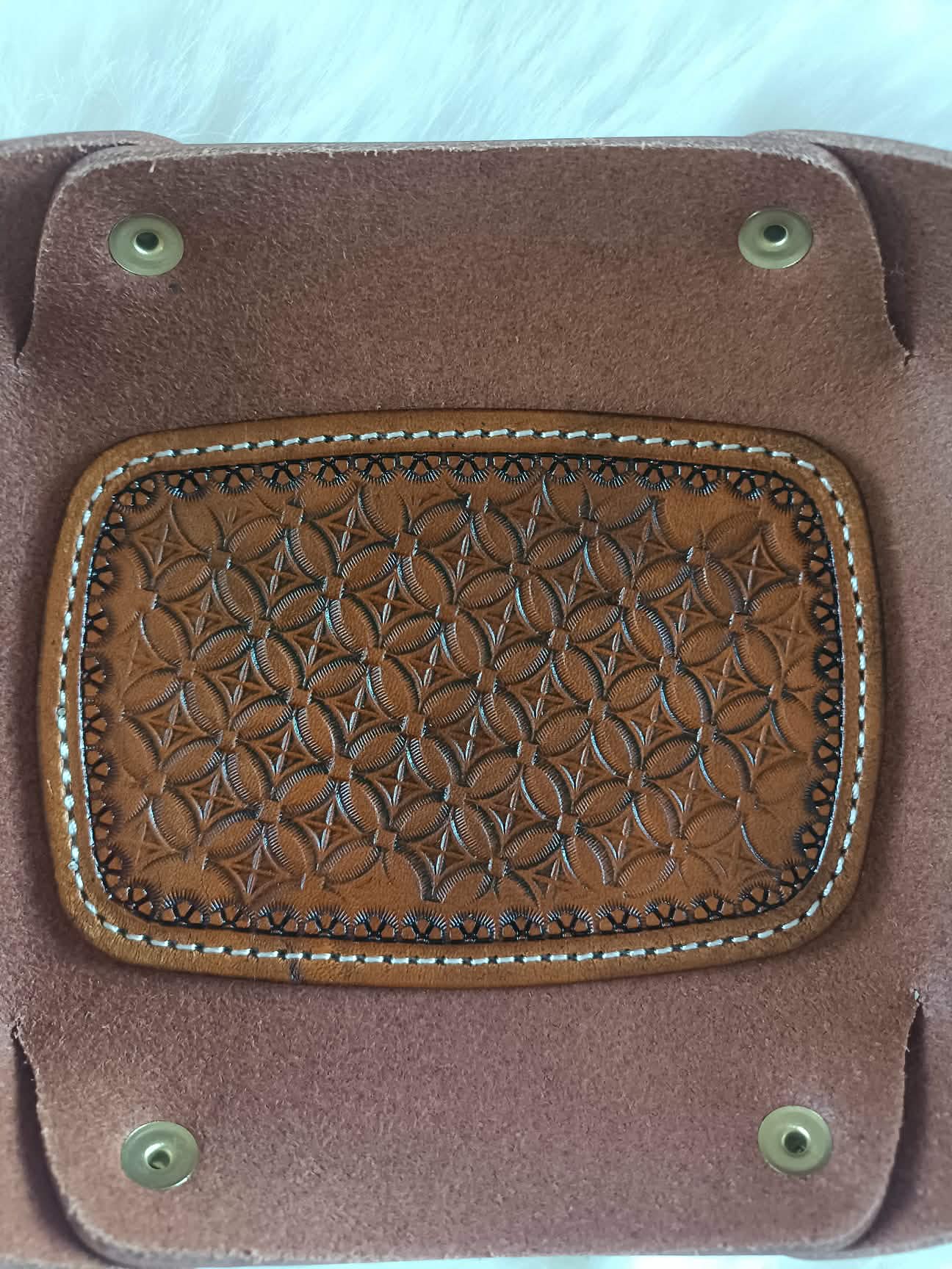 Vide-poche rectangulaire en cuir marron artisanal avec un fond décoré d'un motif tressé (basket weave) repoussé à la main et des coutures blanches, dimensions 18x12 cm.