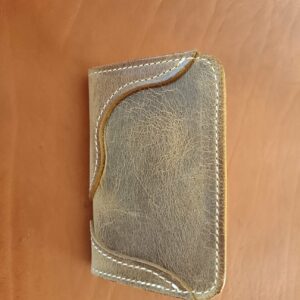 Extérieur porte-cartes en cuir gras brun avec découpes design et couture sellier blanche.