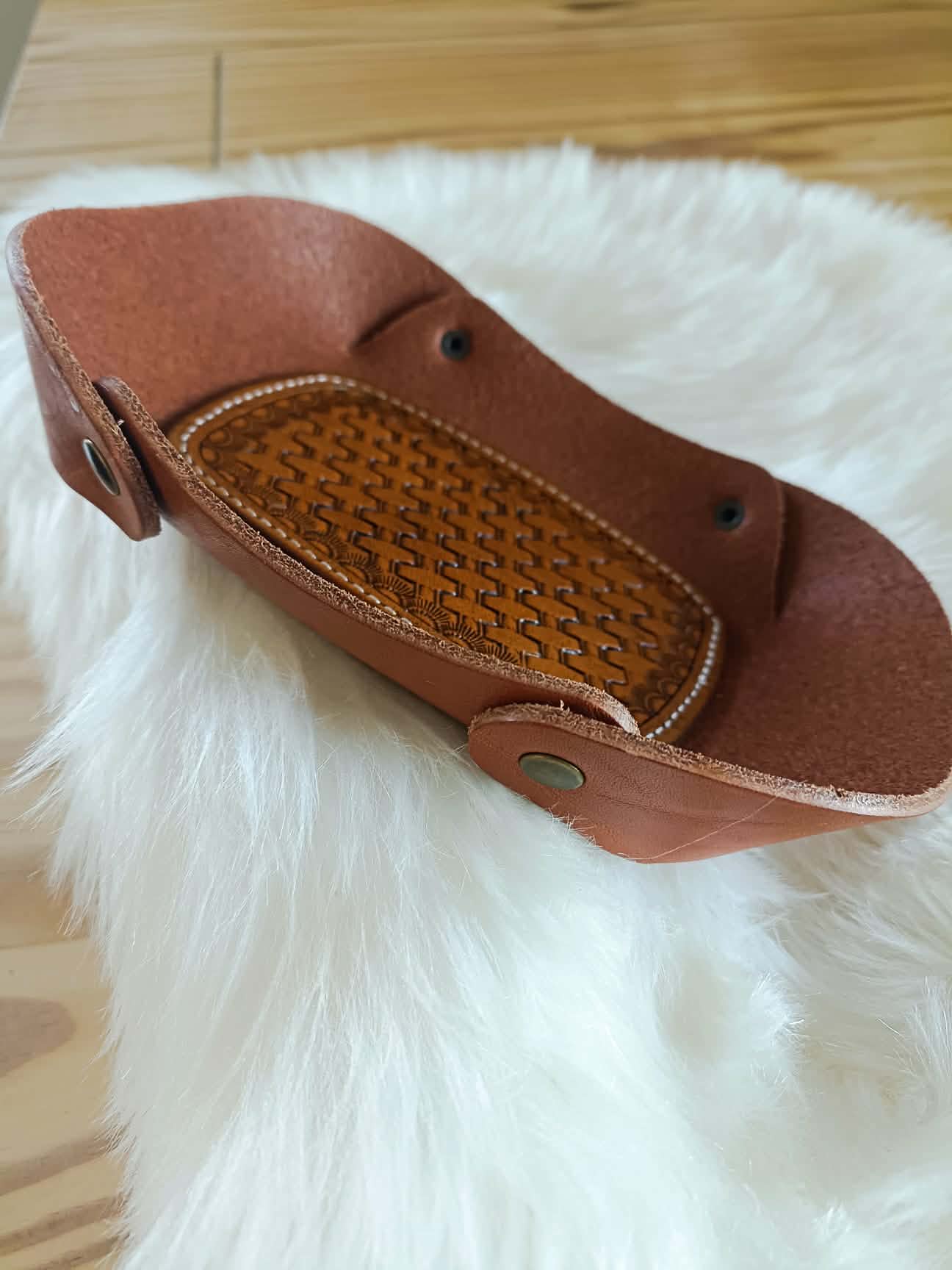 Vide-poche rectangulaire en cuir marron artisanal avec un fond décoré d'un motif tressé (basket weave) repoussé à la main et des coutures blanches, dimensions 18x12 cm.