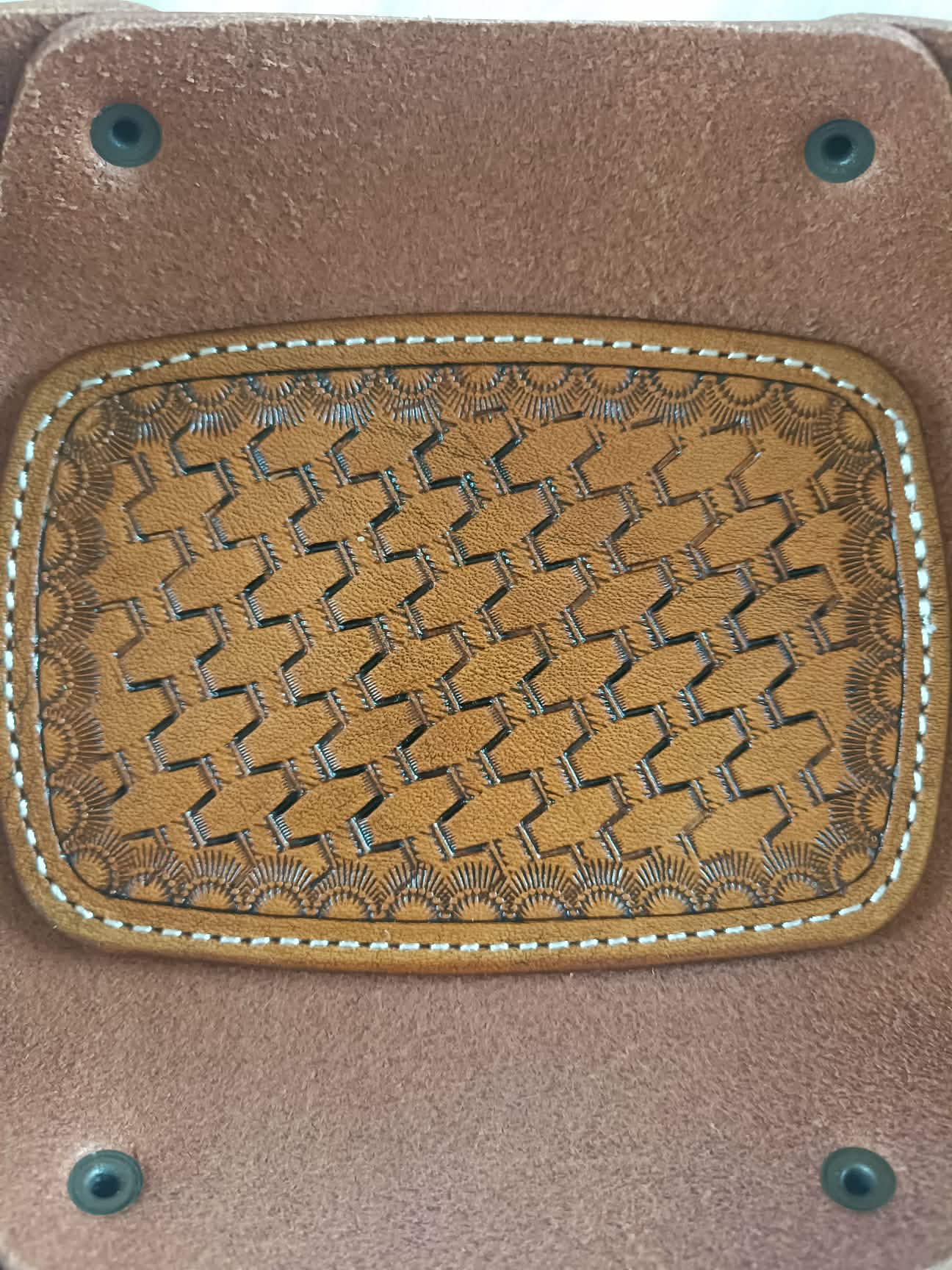 Vide-poche rectangulaire en cuir marron artisanal avec un fond décoré d'un motif tressé (basket weave) repoussé à la main et des coutures blanches, dimensions 18x12 cm.