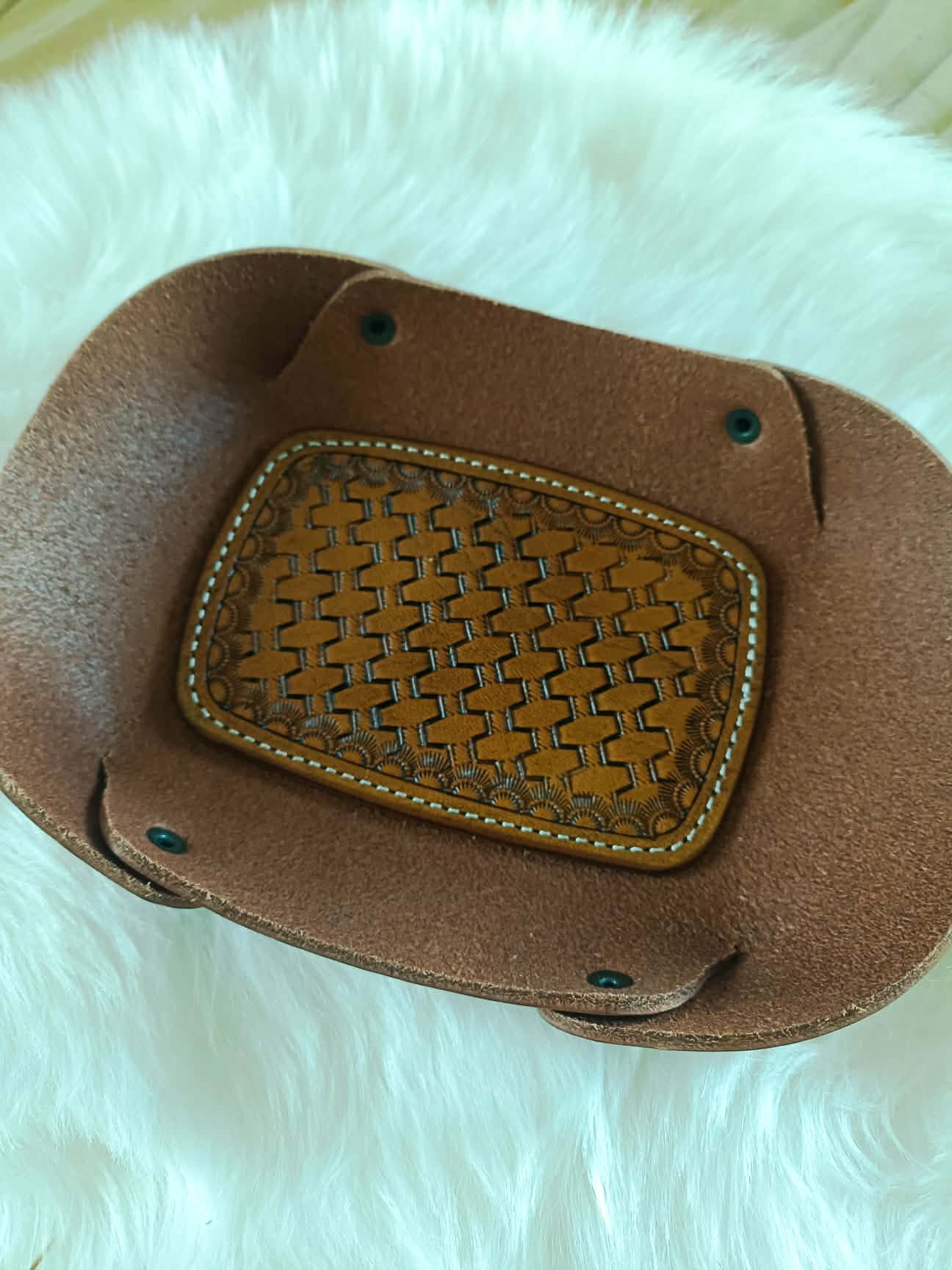 Vide-poche rectangulaire en cuir marron artisanal avec un fond décoré d'un motif tressé (basket weave) repoussé à la main et des coutures blanches, dimensions 18x12 cm.