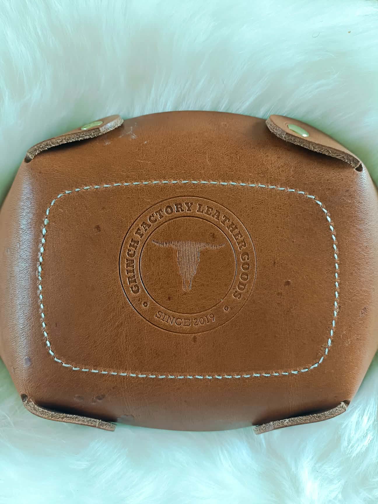 Vide-poche rectangulaire en cuir marron artisanal avec un fond décoré d'un motif tressé (basket weave) repoussé à la main et des coutures blanches, dimensions 18x12 cm.